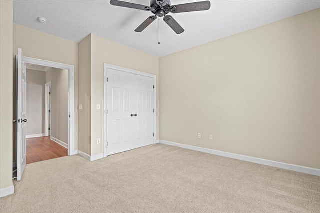 unfurnished bedroom with a textured ceiling, a closet, ceiling fan, and light colored carpet