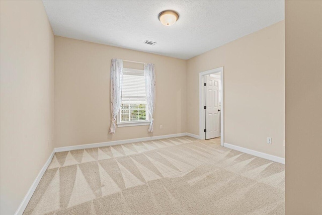 unfurnished room featuring a textured ceiling and light colored carpet