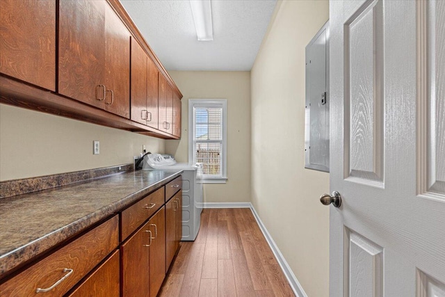 washroom featuring cabinets, a textured ceiling, electric panel, and light hardwood / wood-style flooring