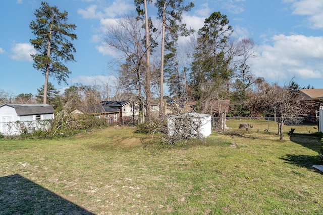 view of yard featuring a storage shed, fence, and an outbuilding