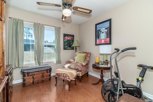 sitting room featuring ceiling fan, a textured ceiling, baseboards, and wood finished floors