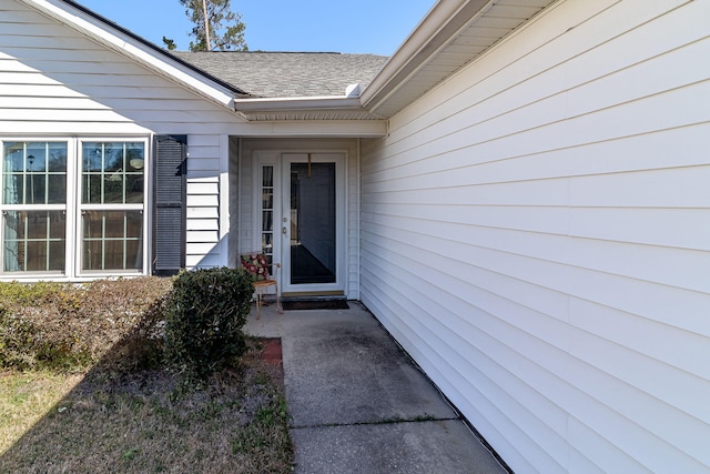 entrance to property featuring roof with shingles