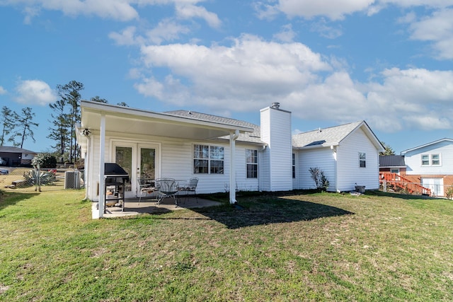 back of house with fence, french doors, a lawn, a chimney, and a patio area