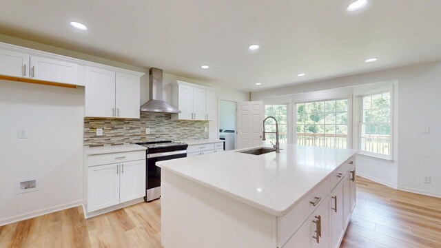 122 Ehrlich Farm Rd, Swainsboro, GA 30401 - kitchen with wall chimney range hood, stainless steel electric stove, decorative backsplash, light wood-style flooring, and white cabinetry