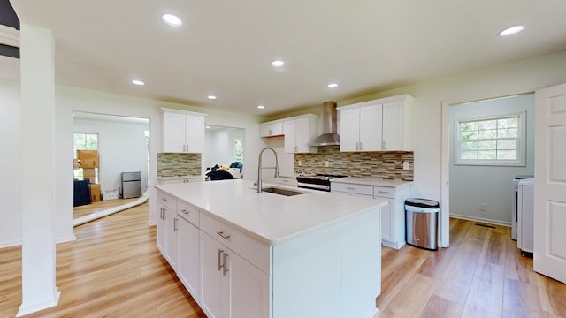 122 Ehrlich Farm Rd, Swainsboro, GA 30401 - kitchen featuring wall chimney range hood, stainless steel stove, light wood-style flooring, tasteful backsplash, and light countertops