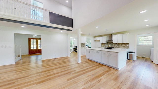 122 Ehrlich Farm Rd, Swainsboro, GA 30401 - kitchen with wall chimney exhaust hood, light wood-type flooring, white cabinetry, light countertops, and a kitchen island with sink