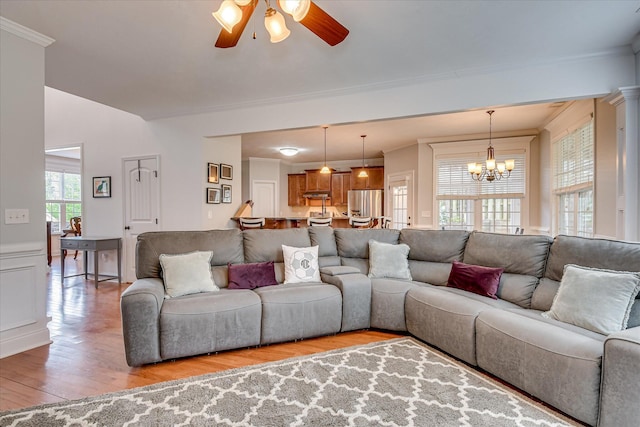 living room with a chandelier, light wood finished floors, ceiling fan, and crown molding