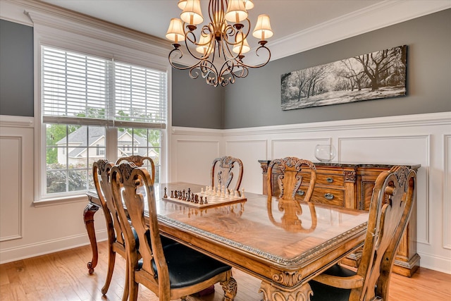 dining room featuring a decorative wall, a chandelier, light wood-type flooring, crown molding, and a wainscoted wall