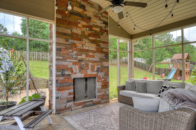 sunroom / solarium with a ceiling fan, lofted ceiling, and an outdoor living space with a fireplace