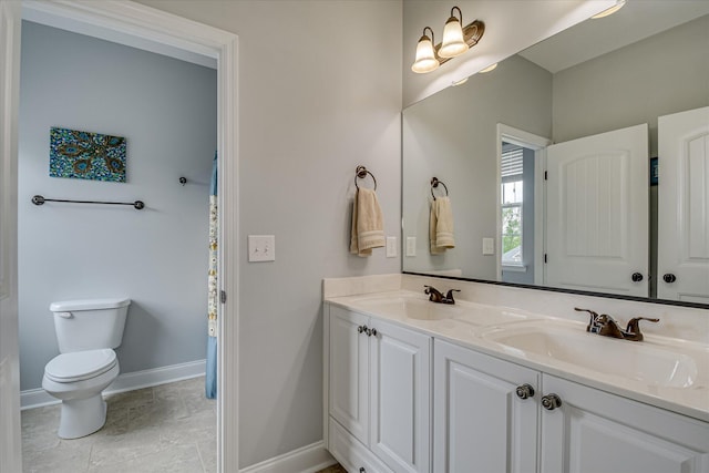 full bath with toilet, double vanity, and baseboards
