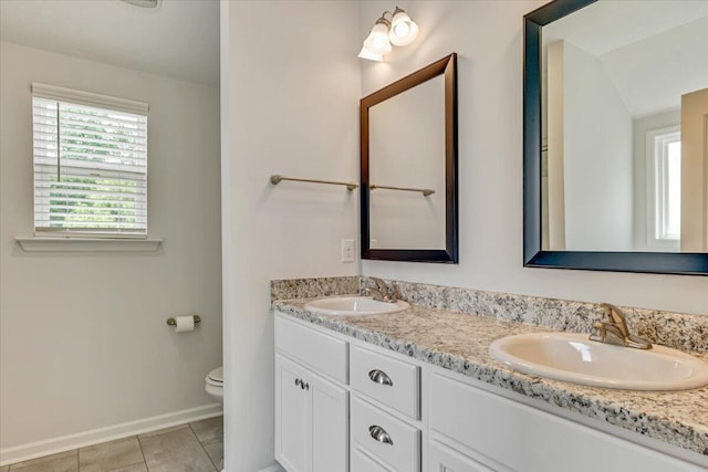full bath with a sink, baseboards, toilet, and double vanity