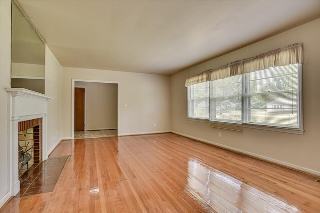 unfurnished living room with a tile fireplace and light wood-type flooring