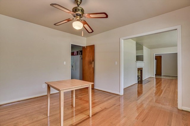 unfurnished room featuring ceiling fan, light wood-type flooring, and a fireplace