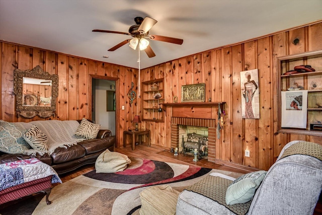 living room with hardwood / wood-style floors, ceiling fan, wood walls, and a fireplace