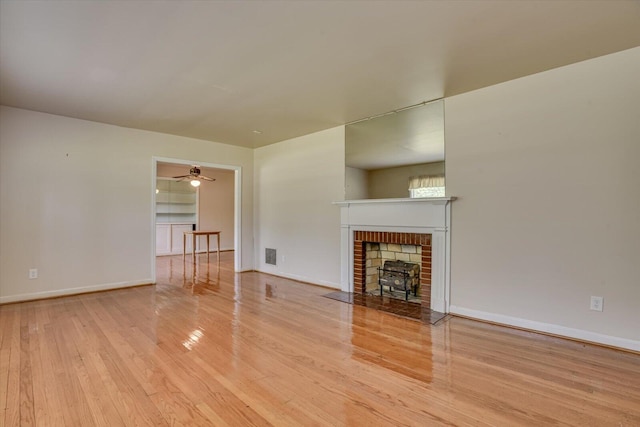 unfurnished living room featuring ceiling fan, a fireplace, and light wood-type flooring