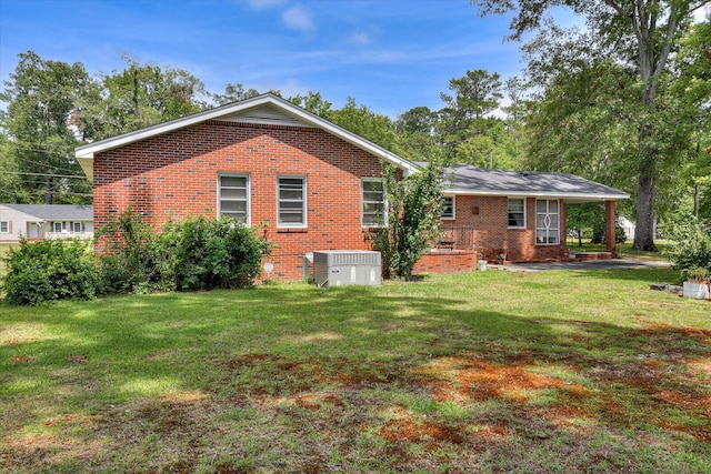 back of property with central air condition unit and a yard