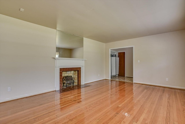 unfurnished living room with light hardwood / wood-style floors and a brick fireplace