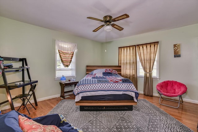 bedroom featuring multiple windows, hardwood / wood-style flooring, and ceiling fan