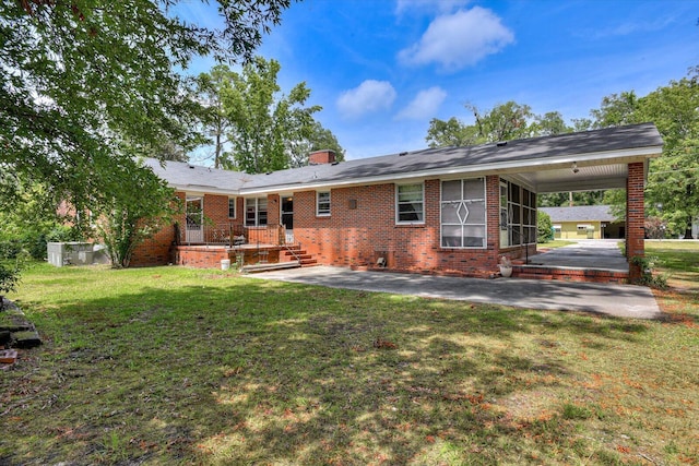 back of property with a lawn and a carport