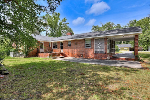 413 Dixie Dr, Thomson, GA 30824 - rear view of property featuring brick siding, a carport, a lawn, a sunroom, and a patio area
