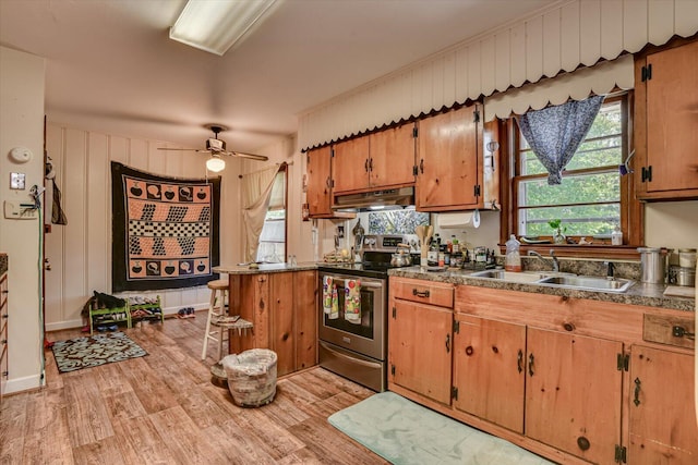 kitchen with ceiling fan, wooden walls, sink, electric stove, and light hardwood / wood-style floors