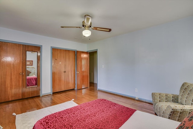 bedroom with ceiling fan, two closets, and light wood-type flooring