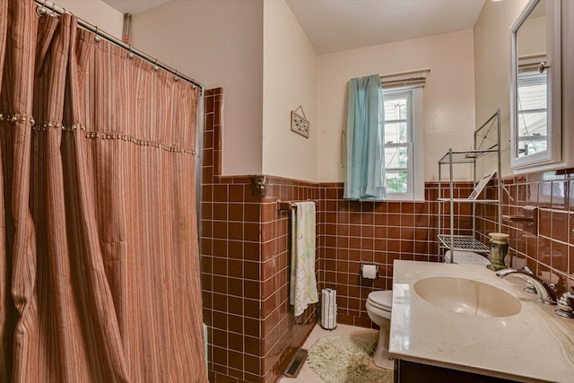 bathroom with walk in shower, vanity, toilet, and tile walls