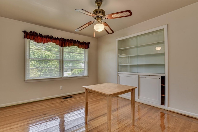 unfurnished office with ceiling fan and light wood-type flooring