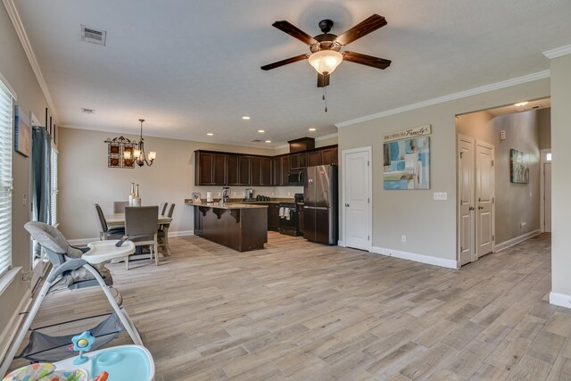 kitchen with dark brown cabinetry, hanging light fixtures, light hardwood / wood-style flooring, a breakfast bar area, and appliances with stainless steel finishes