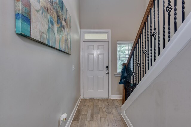 foyer entrance with a towering ceiling and light hardwood / wood-style floors