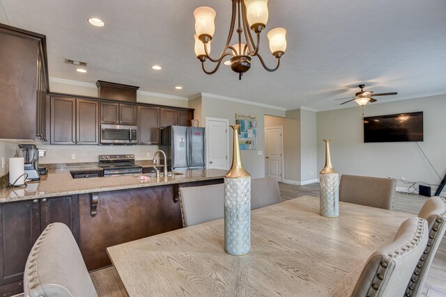 dining room featuring light hardwood / wood-style flooring, ornamental molding, ceiling fan with notable chandelier, and sink
