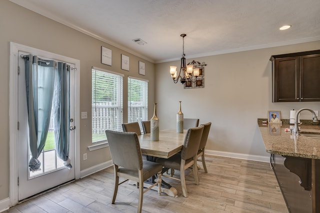 dining space featuring ornamental molding, sink, and a chandelier