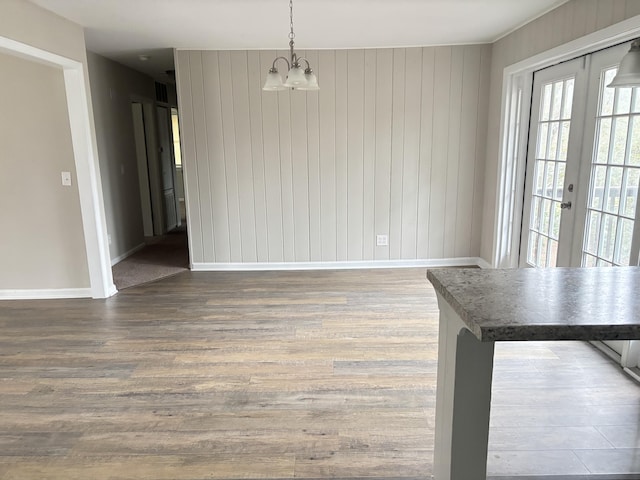 unfurnished dining area featuring french doors, a chandelier, and dark hardwood / wood-style floors