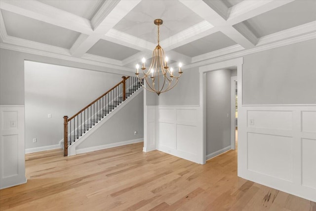 unfurnished dining area with coffered ceiling, an inviting chandelier, beam ceiling, and light hardwood / wood-style flooring