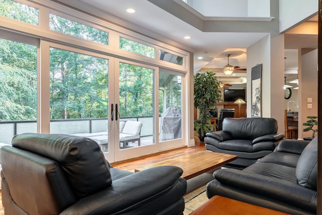 living room with ceiling fan, french doors, a towering ceiling, and light hardwood / wood-style flooring