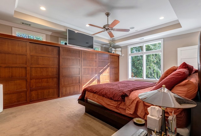 carpeted bedroom with ceiling fan and a raised ceiling