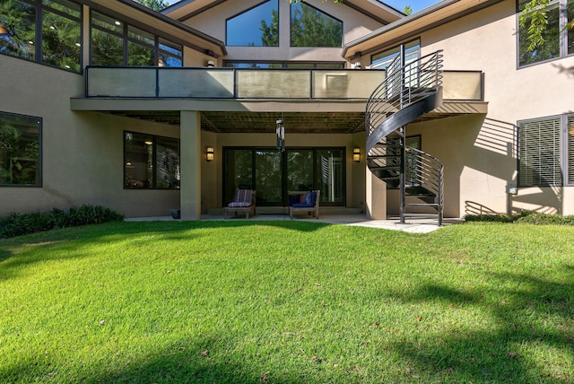 rear view of house with a lawn, a balcony, and a patio