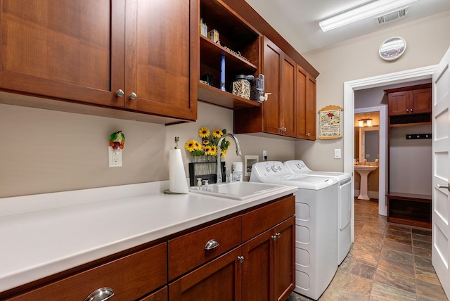 clothes washing area featuring cabinets, washing machine and clothes dryer, and sink