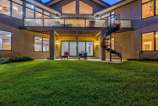 rear view of property with a patio, a balcony, and a lawn