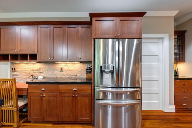 kitchen with backsplash, stainless steel fridge with ice dispenser, dark stone counters, and dark wood-type flooring