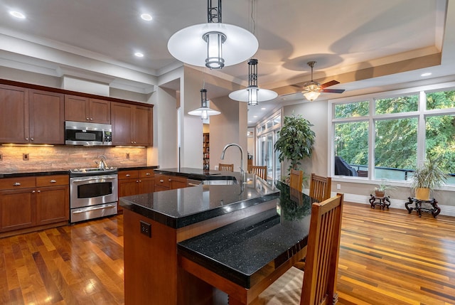 kitchen featuring ceiling fan, sink, pendant lighting, a center island with sink, and appliances with stainless steel finishes