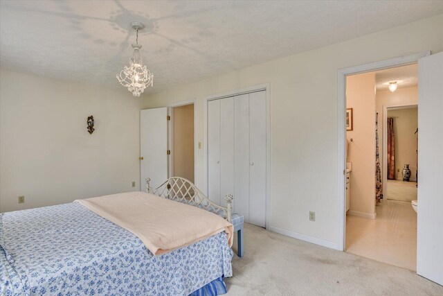 carpeted bedroom featuring a closet, a textured ceiling, and an inviting chandelier