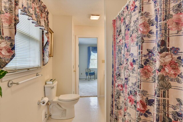 bathroom with a shower with curtain, a textured ceiling, and toilet