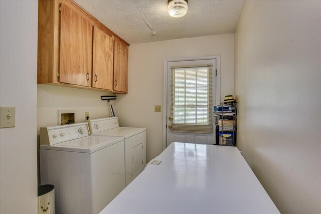 laundry area featuring separate washer and dryer, cabinets, and a textured ceiling