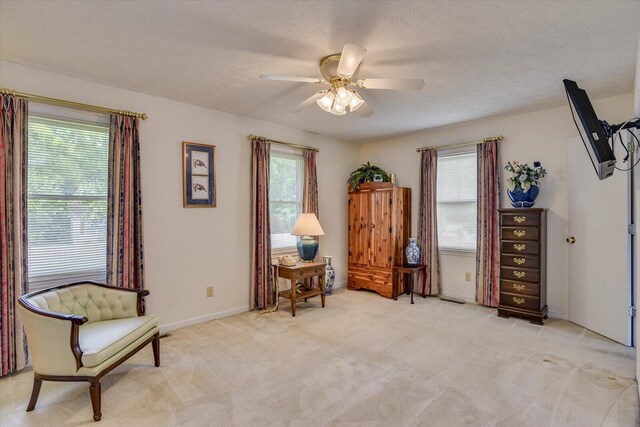 living area featuring a textured ceiling, light colored carpet, and ceiling fan