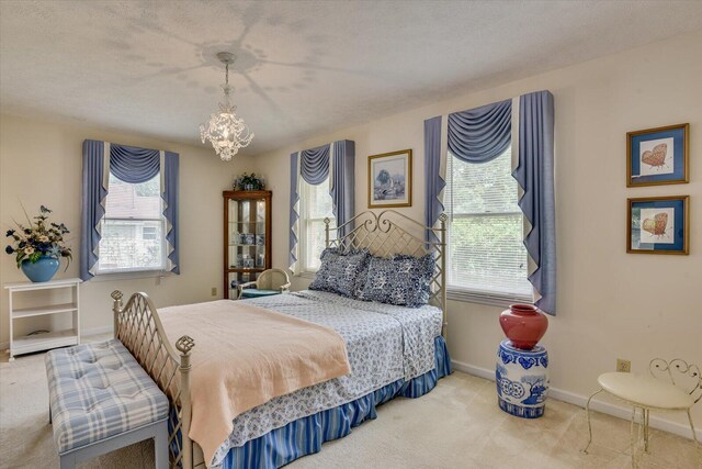 carpeted bedroom featuring a textured ceiling and a notable chandelier