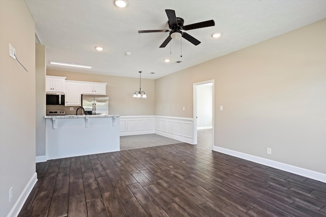 unfurnished living room featuring sink and ceiling fan with notable chandelier