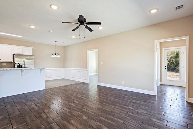 unfurnished living room featuring ceiling fan with notable chandelier