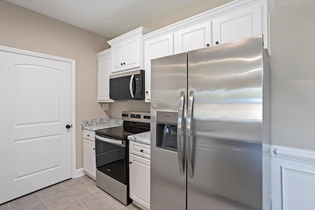 kitchen featuring light stone countertops, appliances with stainless steel finishes, light tile patterned floors, and white cabinets