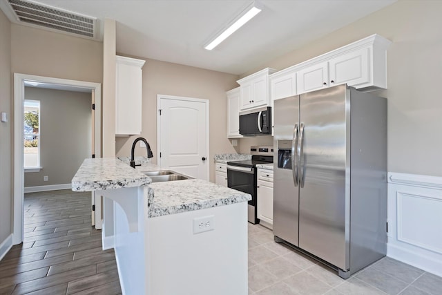 kitchen with appliances with stainless steel finishes, sink, white cabinets, a kitchen breakfast bar, and kitchen peninsula